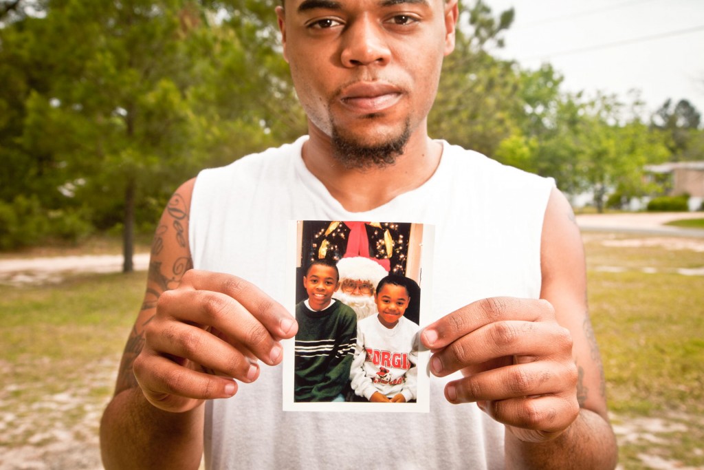 Shavon Patterson holding up photos of him and his brother Justin Patterson